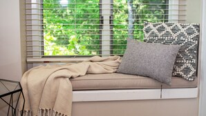 A window seat with a beige throw blanket, a grey pillow, and a patterned pillow.