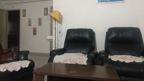 Un salón con dos sillones de cuero negro, una mesa de centro de madera y una pared blanca decorada con cuadros.