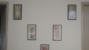 Una pared con cinco obras de arte enmarcadas.