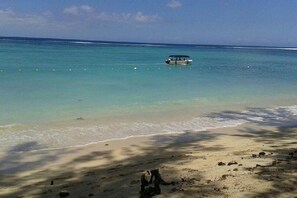 Uma praia com águas turquesa cristalinas, um barco e uma costa arenosa.