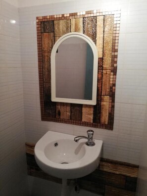 A bathroom with a white sink, a mirror, and a mosaic tile backsplash.
