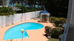 Piscina com área central rebaixada, cercada por um muro branco e um pequeno gazebo.