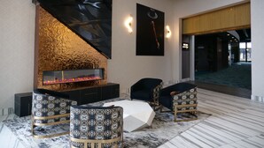 A modern lobby with a fireplace, patterned chairs, and a geometric coffee table. - Great River Hotel (Burlington)