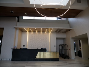 A reception area with a modern design, featuring a reception desk, geometric wall patterns, and a ceiling with circular light fixtures. - The Catfish Bend Inn & Spa (Burlington)