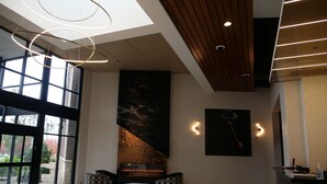 A modern lobby with a fireplace, seating area, and large windows. - Great River Hotel (Burlington)