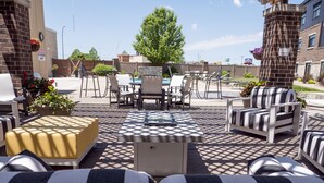 An outdoor patio with striped sofas, a yellow ottoman, and a pool table. - Great River Hotel (Burlington)