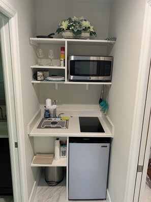 Enjoy cooking in this kitchenette equipped with a microwave, refrigerator, and sink with a soap dispenser.