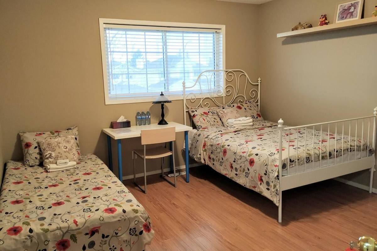 A bedroom with two single beds, a desk, and a chair.