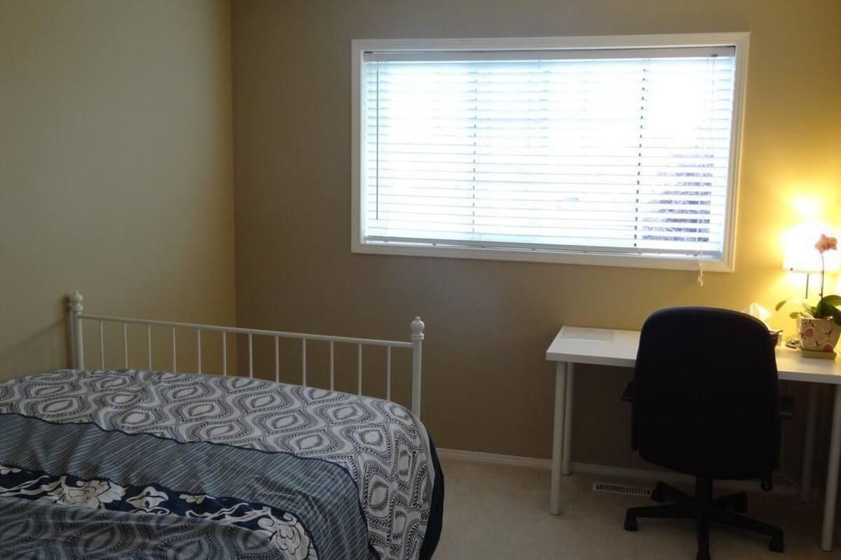 A bedroom with a bed, a desk, and a chair.