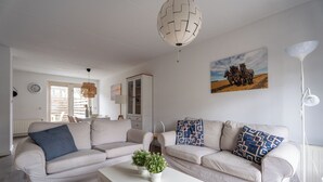 Uma sala de estar com dois sofás, uma mesa de centro e um abajur.