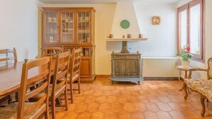 Ein Essbereich mit Holzkohle, einem Tisch, einem Schrank mit Glastüren, einem Kamin und einem Fenster mit Blick.