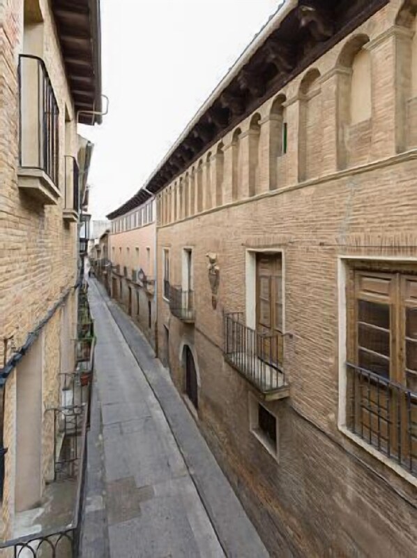 Una calle estrecha bordeada por edificios históricos con fachadas de piedra y ventanas arqueadas.