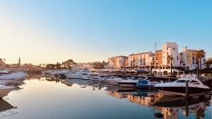 Un port de plaisance où sont amarrés de nombreux bateaux, entouré d’immeubles dotés de balcons, sous un ciel dégagé.