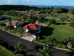 A residential area with multiple houses, a road, and a view of the ocean. - Casa Boroda - Andromeda Pedasi - In Park with Swimming pool and Beach (Pedasi)