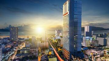 A high-rise building with a modern design, surrounded by other buildings and a busy street with light trails.