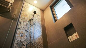 Una ducha con pared de azulejos estampados, un perchero y una ventana pequeña.