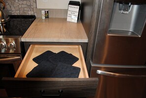 Una cocina con un refrigerador de acero inoxidable, una encimera de madera y un cajón con alfombrillas negras.