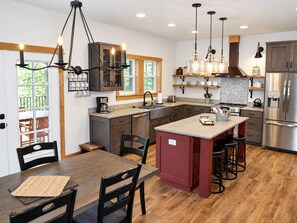 A modern kitchen with a central island, dark cabinetry, and pendant lighting.