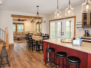 A modern kitchen with a wooden dining area, bar stools, and a coffee station.