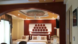 A hotel room with two beds, a desk, chairs, a ceiling fan, and a decorative wall. - Rosemary Boutique (Maafushi)