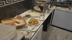 A buffet with various food items including bread, pancakes, and a pie. - Rosemary Boutique (Maafushi)
