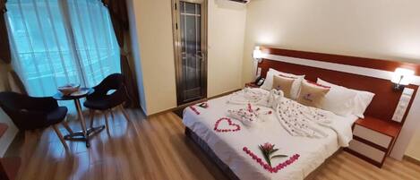 A hotel room with a bed, bedside table, and a desk with chairs.