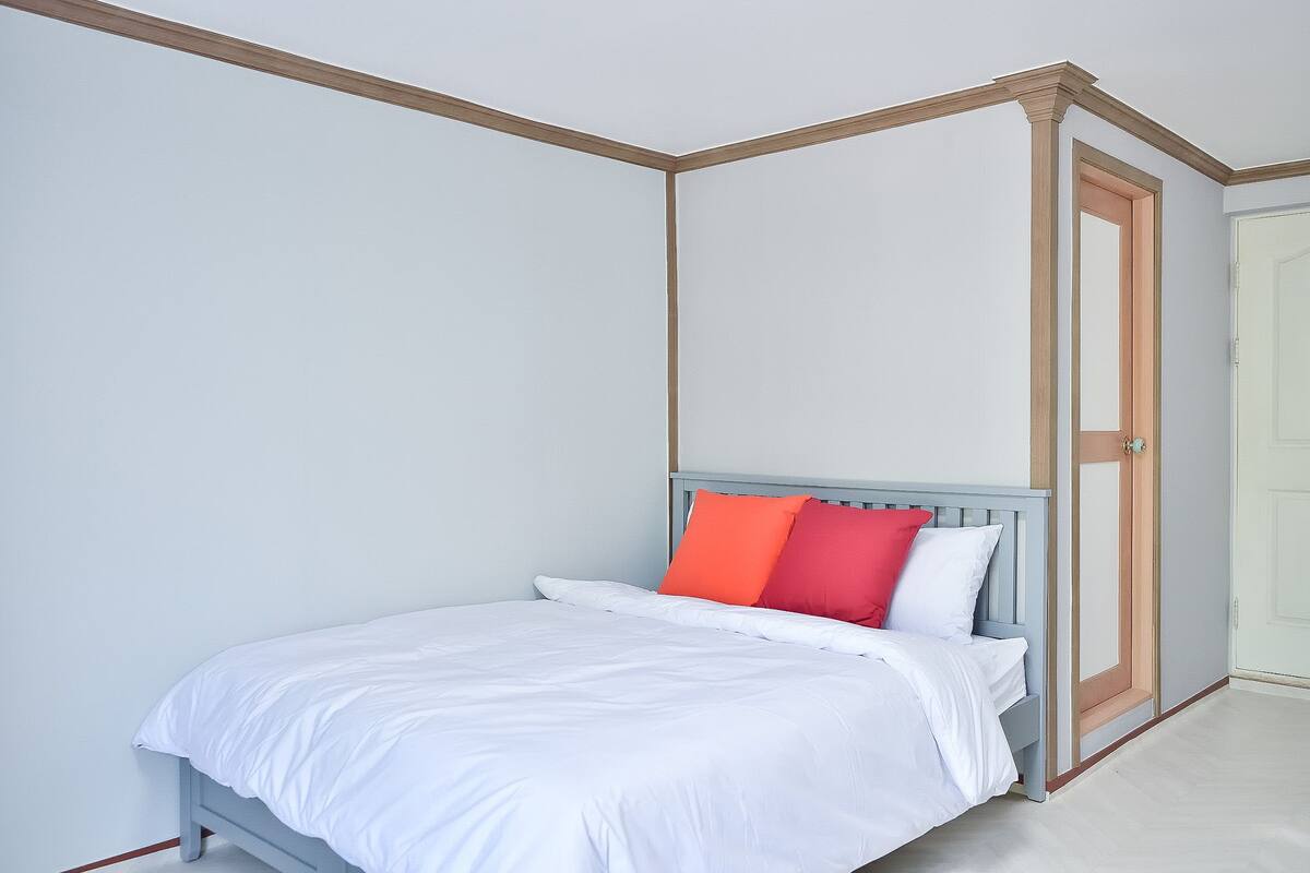 Une chambre à coucher avec un lit, du linge de lit blanc et une porte.