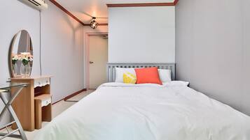 Et soveværelse med seng, kommode, spejl og loftlampe.