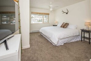 A bedroom with a bed, a desk, a window, a ceiling fan, and a deer antler on the wall. - Beautiful Firelight Chalet-Big Sky Town Center (Big Sky)