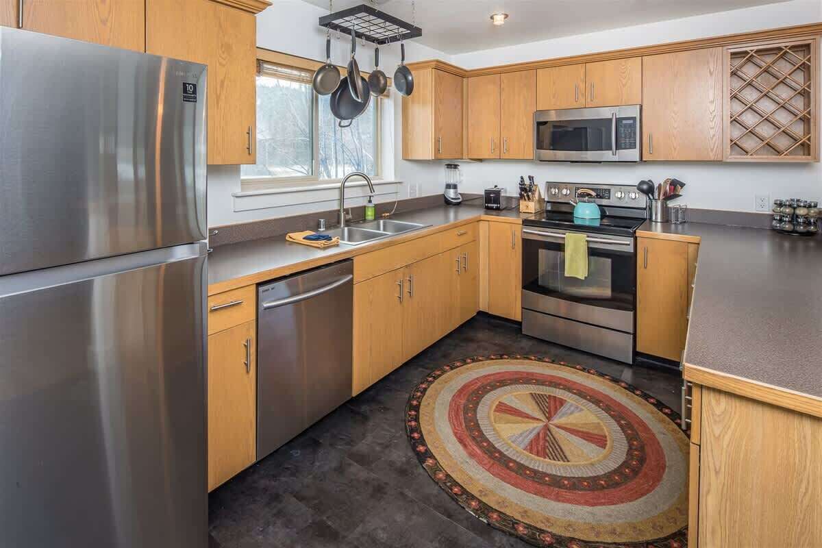 Een moderne keuken met roestvrijstalen apparatuur, houten kastjes en een kamerkleed met dessin.