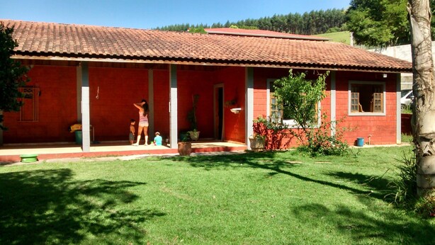 A red building with a tiled roof, a covered porch, and a well-maintained lawn.