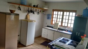 A compact kitchen with a refrigerator, stove, and various kitchen utensils hanging on the wall.