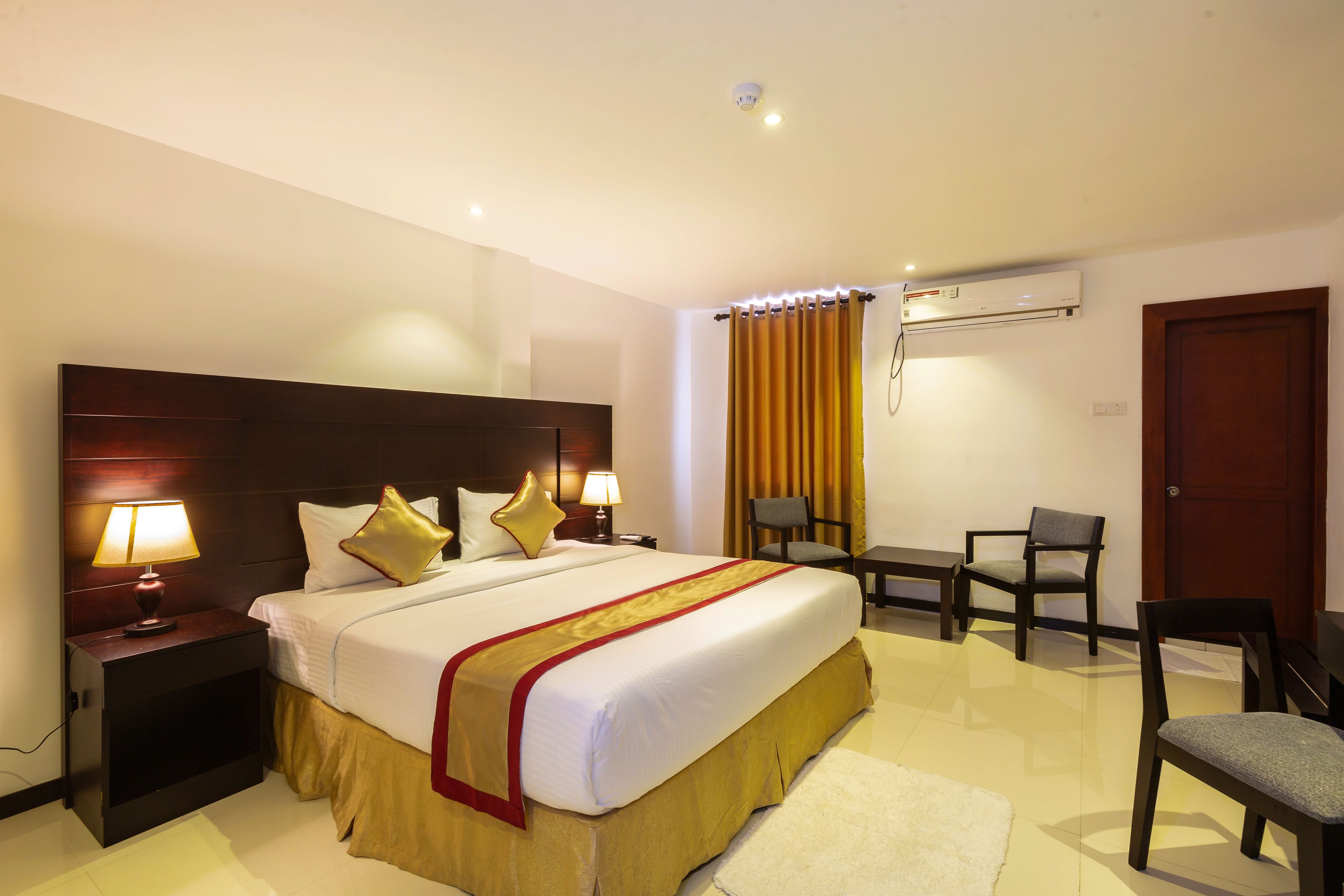 A hotel room with a large bed, bedside tables with lamps, a desk, and a chair.