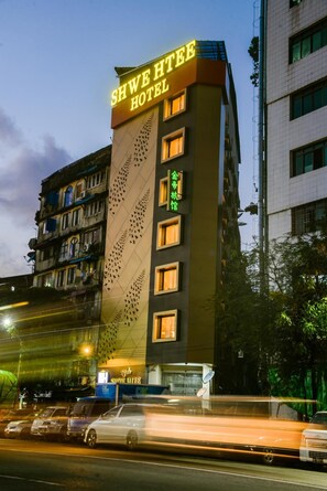 A hotel with a prominent sign reading "SHWE HTEE HOTEL" and a smaller sign below it. - Shwe Htee River View (Yangon)