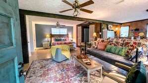 A cozy living room with a sofa, armchair, and a coffee table. There is a ceiling fan and a bed in the background. - The Cottage - 2 miles to I-65 (Montevallo)
