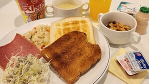 Prato de pequeno-almoço com tosta, fiambre, salada de couve e arroz como acompanhamento.