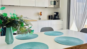 Une cuisine moderne équipée d’un four à micro-ondes, d’une machine à café et agrémentée d’une plante posée sur le plan de travail.