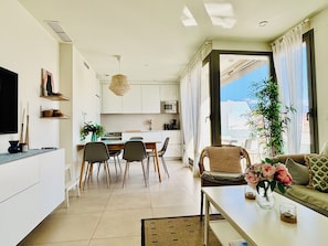 A modern living room with a sofa, coffee table, and dining area.
