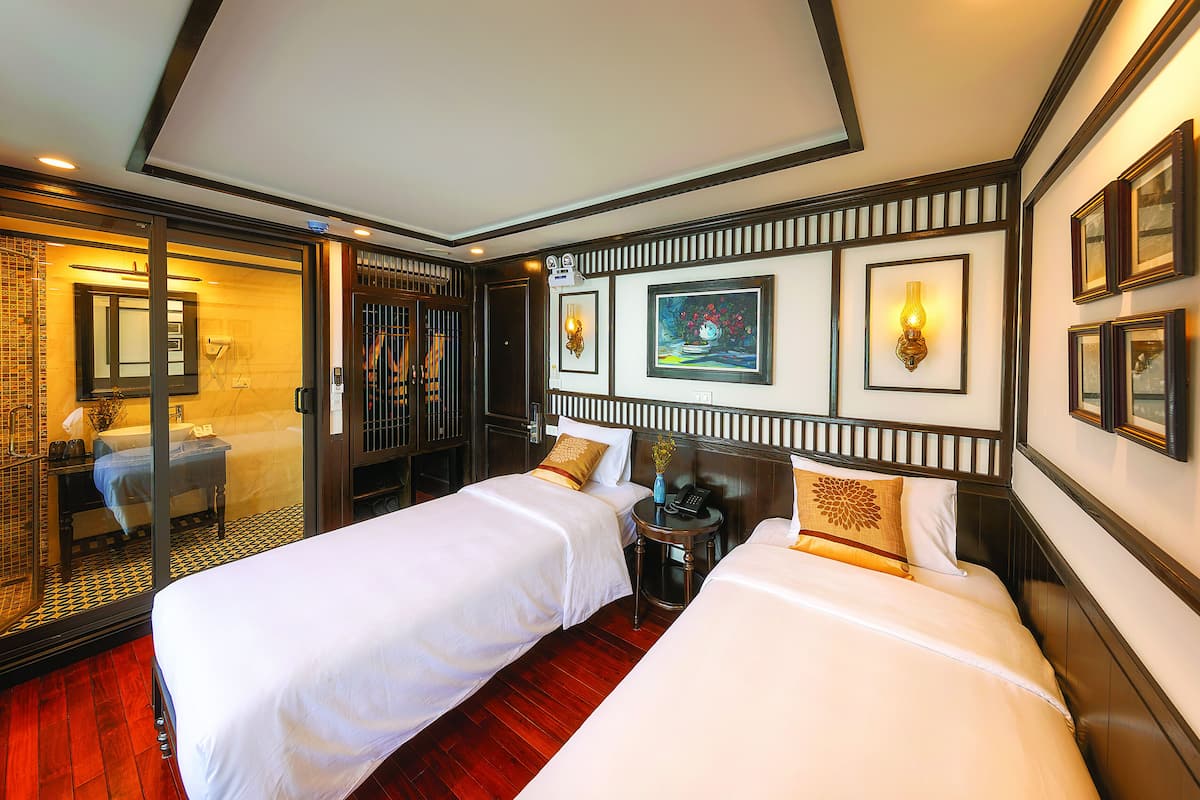 A hotel room with two beds, a bathroom, and a view of the outside.