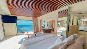 A modern bedroom with a large bed, a bathtub, and a view of the sea. - Esplendor by Wyndham Isla Mujeres Boutique All Inclusive (Isla Mujeres)