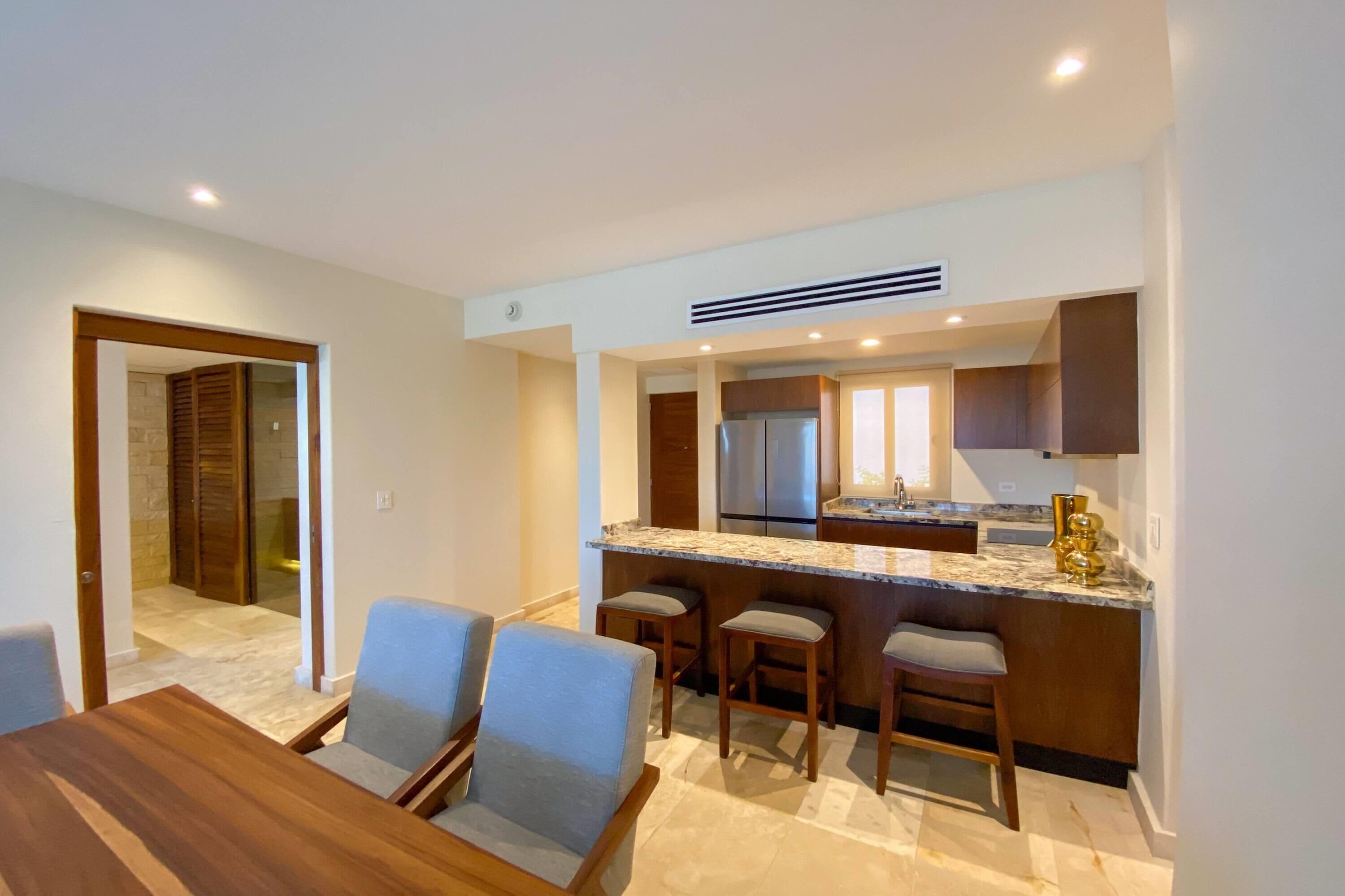 A modern kitchen with a marble countertop, stainless steel appliances, and a bar area.
