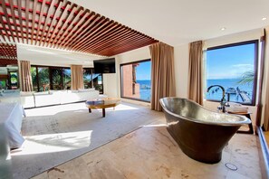 A modern hotel room with a large bathtub, a sofa, a coffee table, and a TV. - Esplendor by Wyndham Isla Mujeres Boutique All Inclusive (Isla Mujeres)