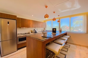 A modern kitchen with a central island, stainless steel appliances, and pendant lighting.