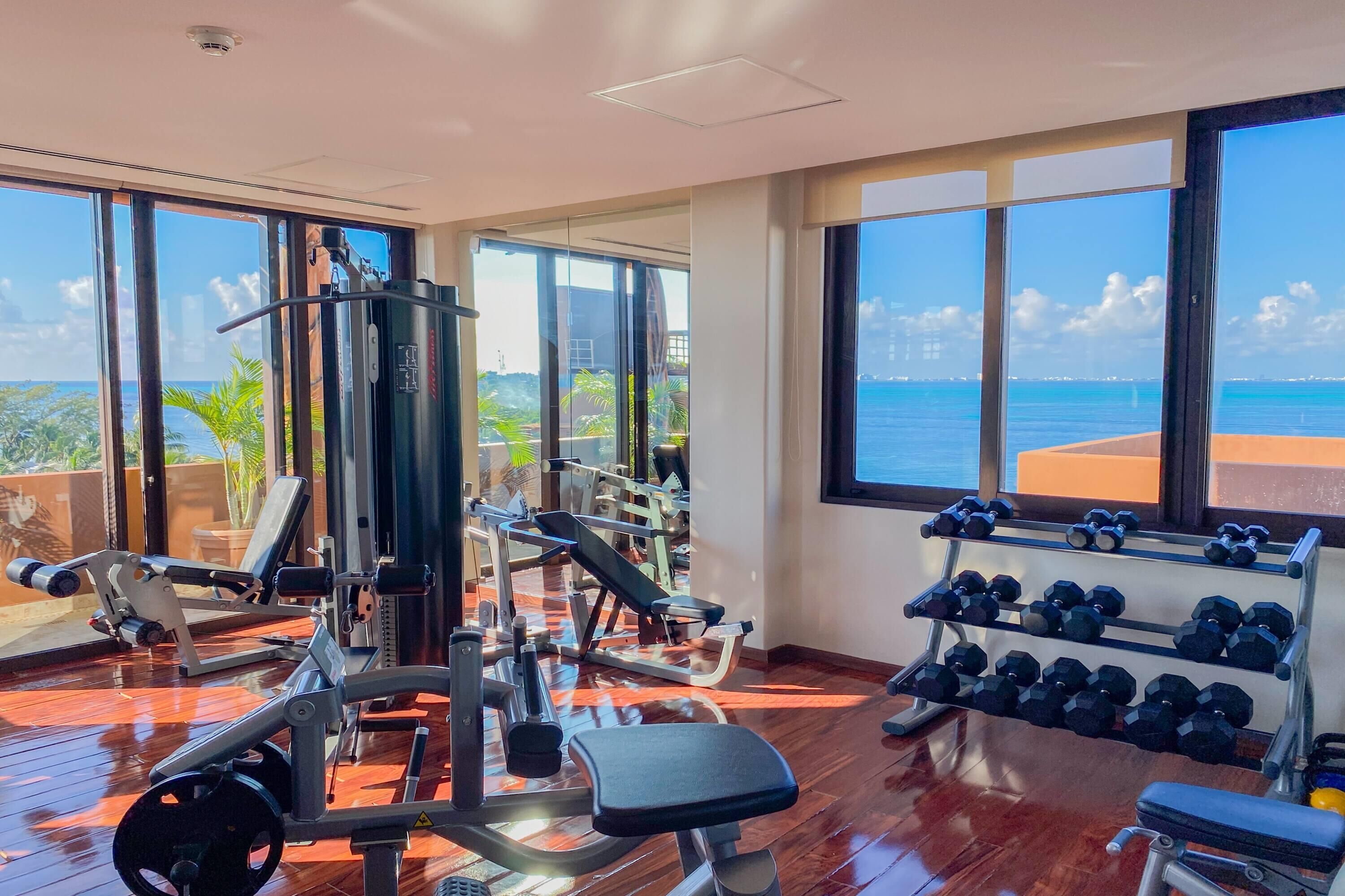 A gym with exercise equipment, a bench, and a rack of dumbbells.