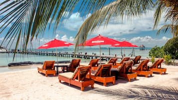 En la playa, arena blanca, sillas reclinables de playa, sombrillas