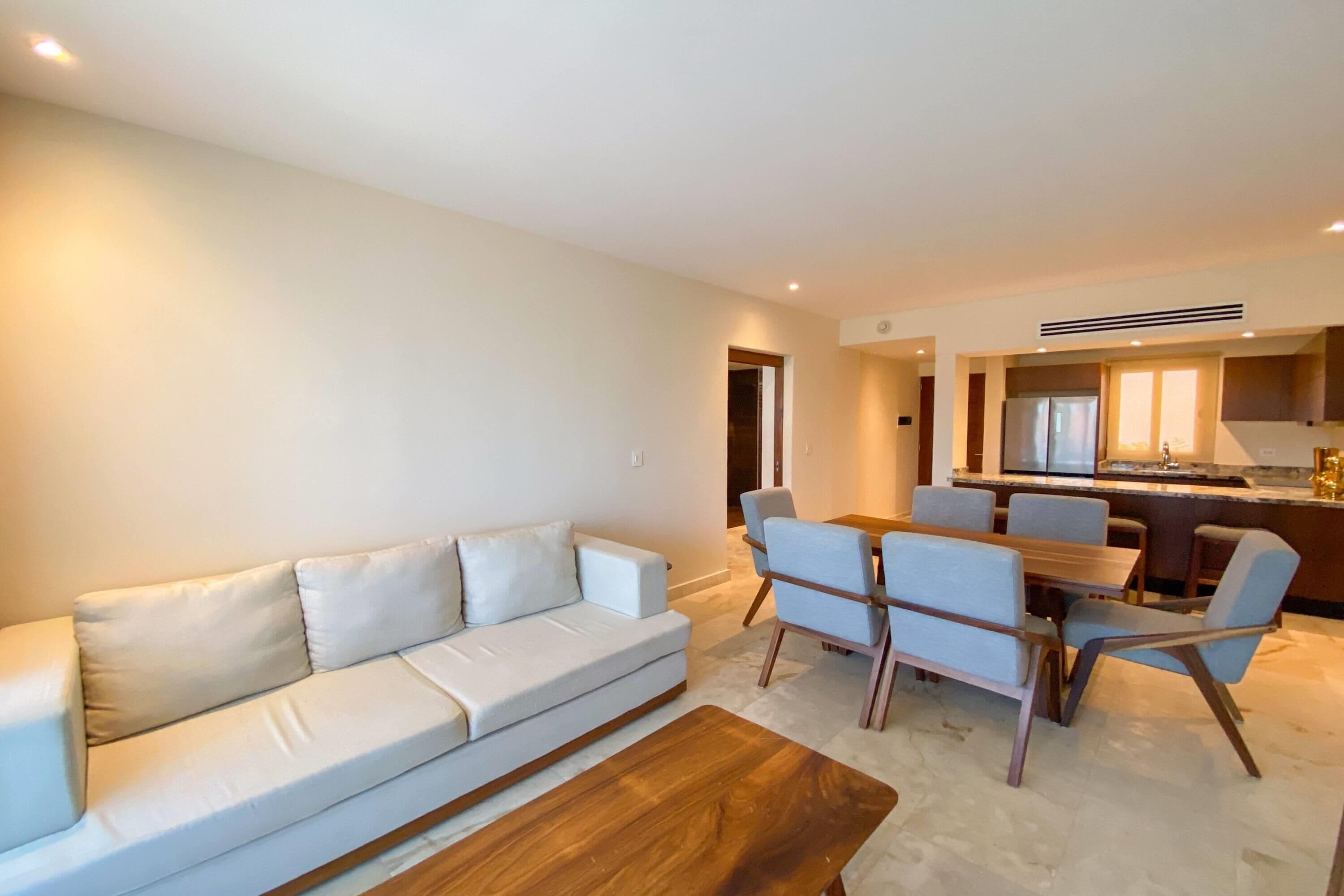 Una sala de estar moderna con un sofá, una mesa de centro y un comedor con sillas y una mesa.