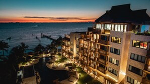 A hotel with a pool, outdoor seating, and a view of the ocean at sunset. - Esplendor by Wyndham Isla Mujeres Boutique All Inclusive (Isla Mujeres)