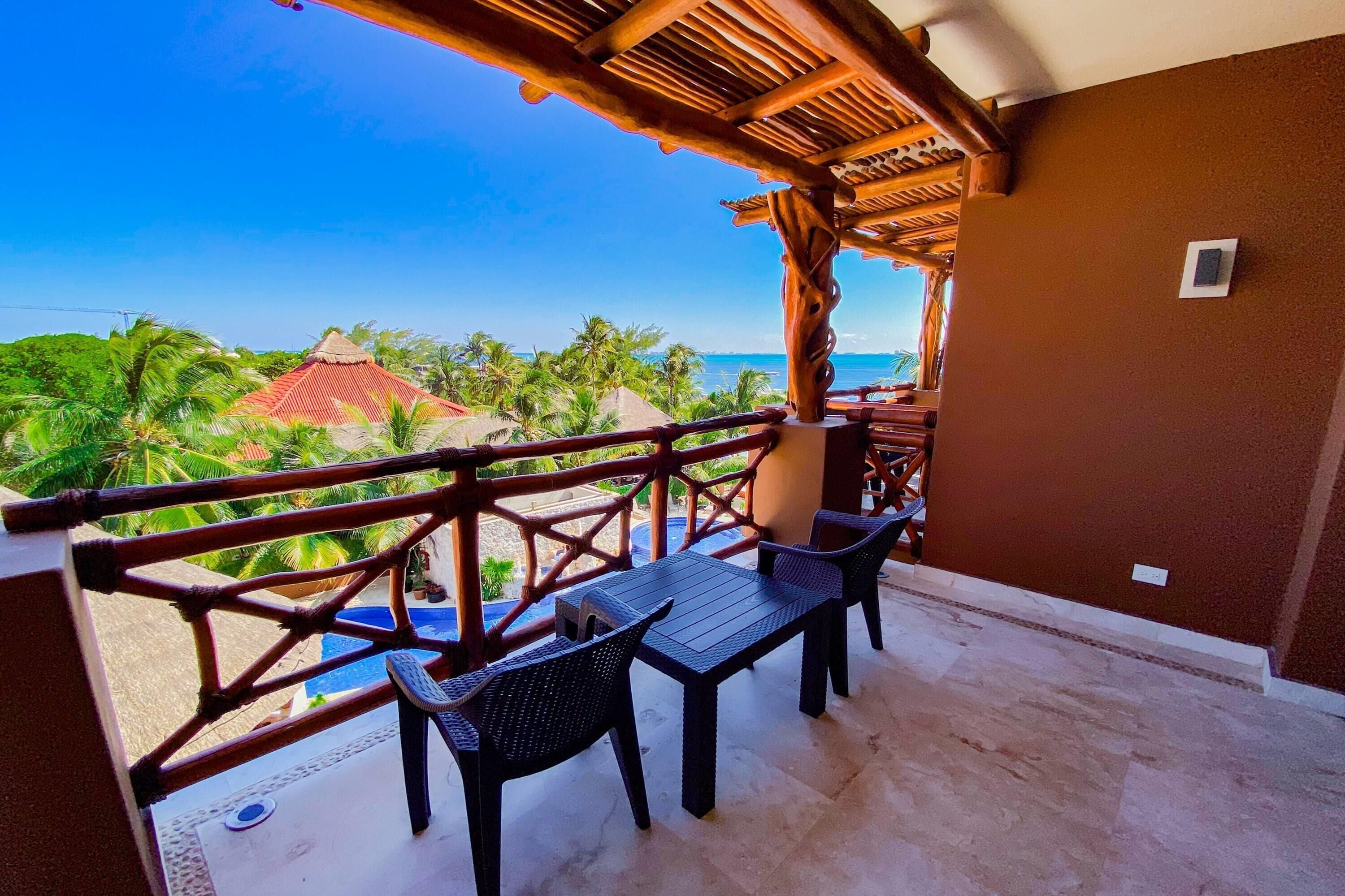 Varanda com vista para a praia, uma mesa e cadeiras.