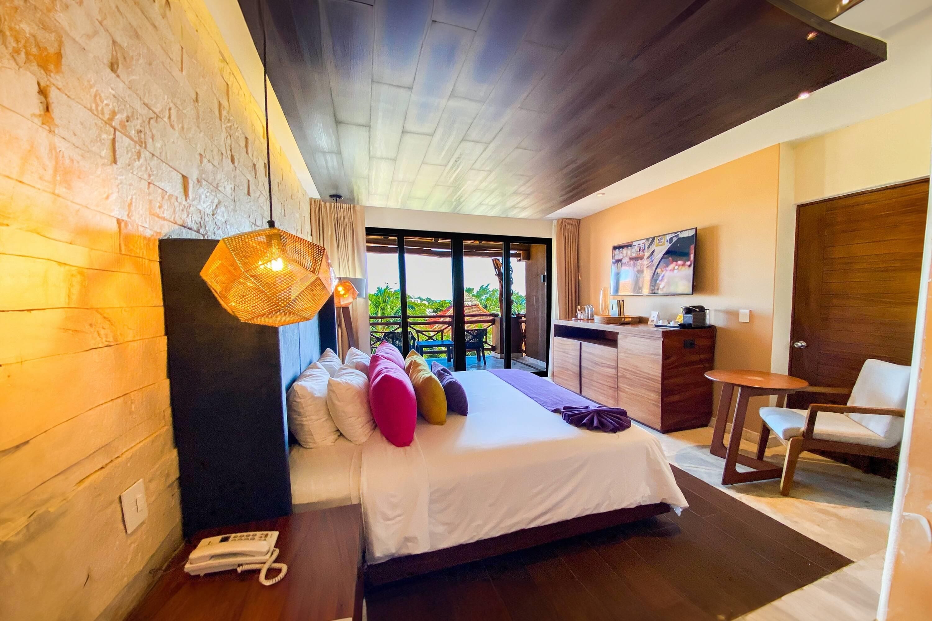 Een moderne hotelkamer met een groot bed, een bureau, een stoel en een balkon met uitzicht.