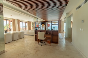 A spacious living area with a wooden desk, a comfortable sofa, and a view of the sea.